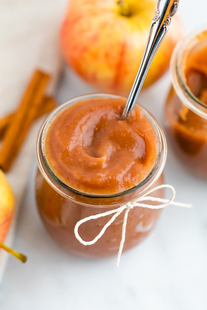 Glass jar filled with apple butter and decorated with a twine bow.