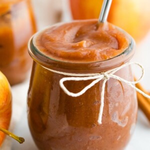 Apple butter in a jar with a twine bow tied around the jar.