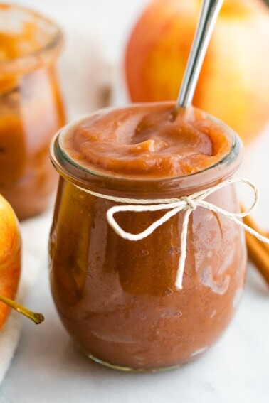 Apple butter in a jar with a twine bow tied around the jar.