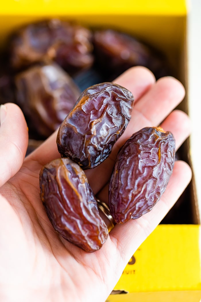 Three medjool dates in a woman's hand.