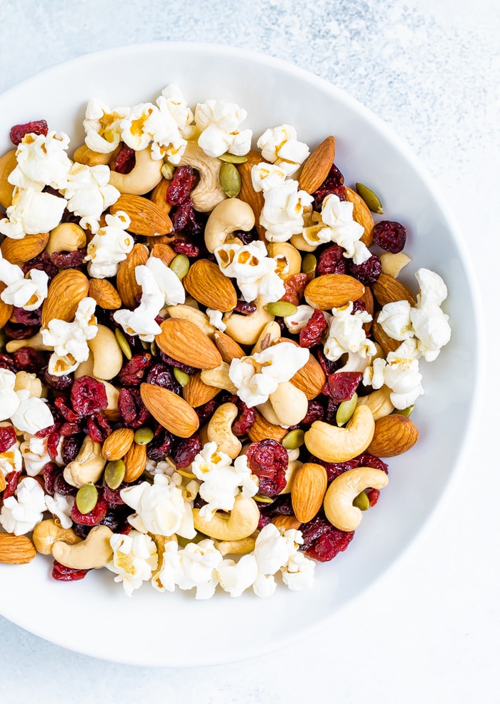 Bowl of trail mix made with popcorn, nuts and cranberries.