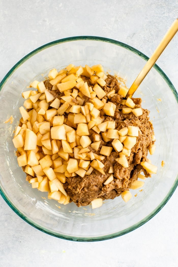 Mixing bowl with apple bread batter and small chopped apples.