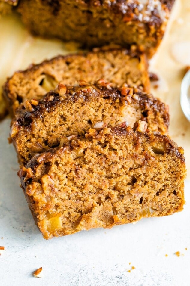 Three slices of apple bread. The top has a crust of cinnamon and pecans.