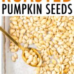 Sheet pan with roasted pumpkin seeds and a spoon.