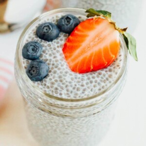 Chia pudding a mason jar topped with a strawberry and blueberries.
