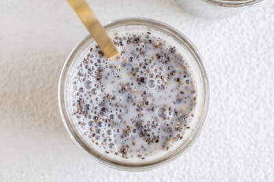 Mason jar with chia seed pudding being mixed and a gold spoon, overhead shot