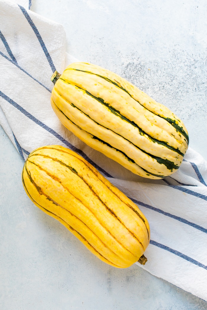 Two delicata squashes on a cloth napkin.