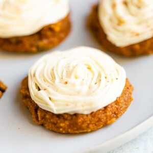 Close up photo of a pumpkin cookie frosted with white icing.