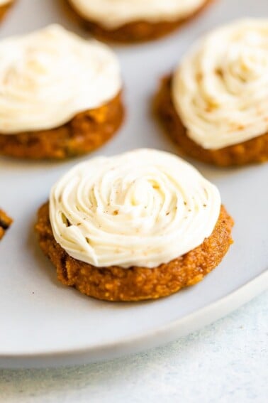 Close up photo of a pumpkin cookie frosted with white icing.