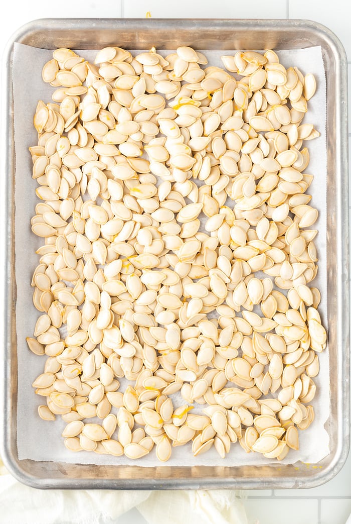 Pumpkin seeds on a baking sheet before being baked.