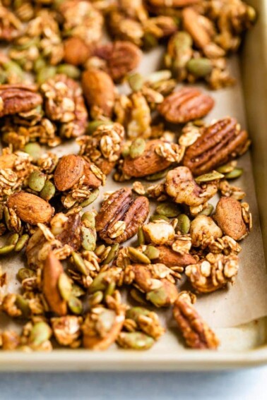 Spiced seeds, nuts and oats on a baking sheet.