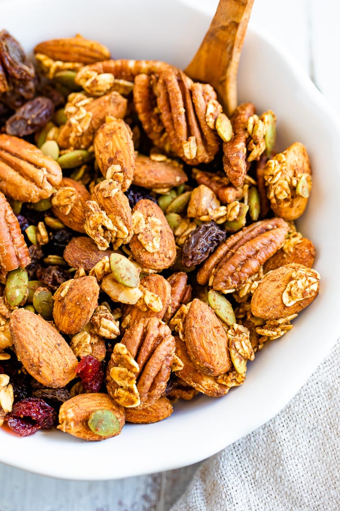 Bowl with a small wooden spoon full of pumpkin spice nutty and fruity trail mix.