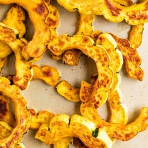 Half moon shapes of roasted delicata squash on a sheet pan.