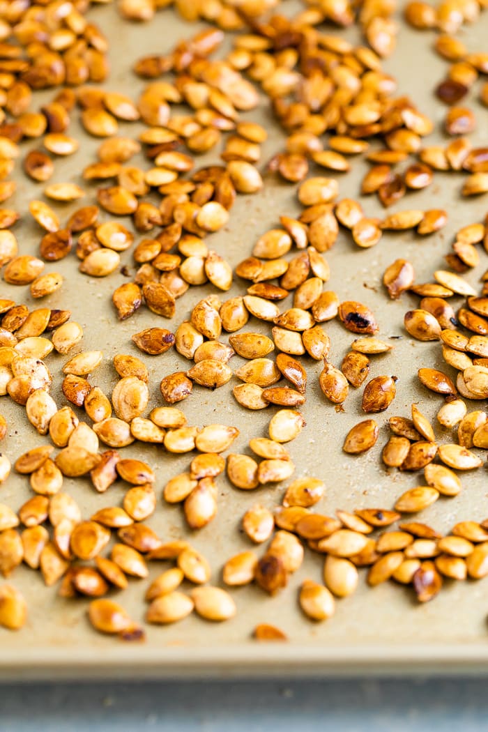 Roasted delicata squash seeds on a sheet pan.