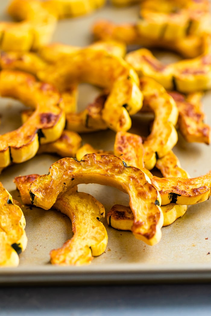 Half moon shapes of roasted delicata squash on a sheet pan.