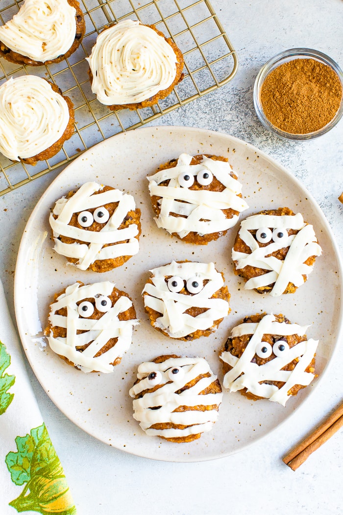 Plate with cute mummy cookies. Pumpkin cookies frosted with stripes of white icing and two candy eyes.