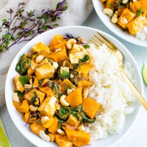 Bowls of tofu pumpkin curry topped with cashews and served with rice.