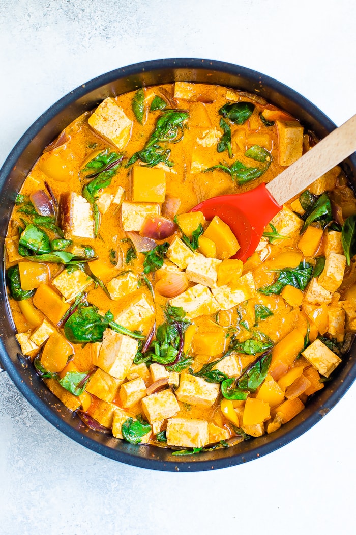 Pot with tofu pumpkin curry and a spoon.