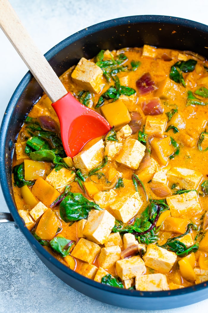 Pot with tofu pumpkin curry and a spoon.