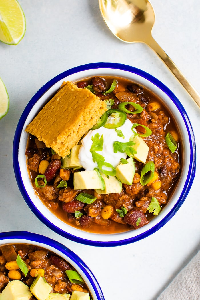 Bowl of turkey chili with sour cream, avocado and cornbread.