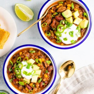 Bowls of turkey chili served with avocado, sou cream and cornbread.