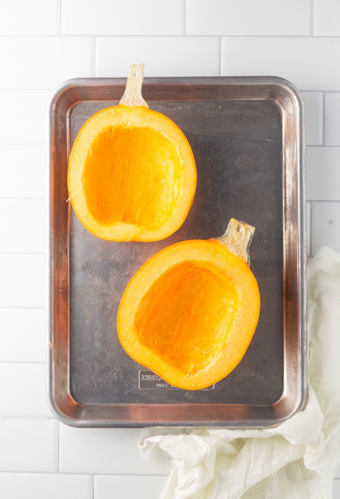 Sheet pan with two halves of pumpkin.