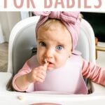 Baby Olivia in a highchair eating a bowl of oatmeal with bananas and peanut butter on top.