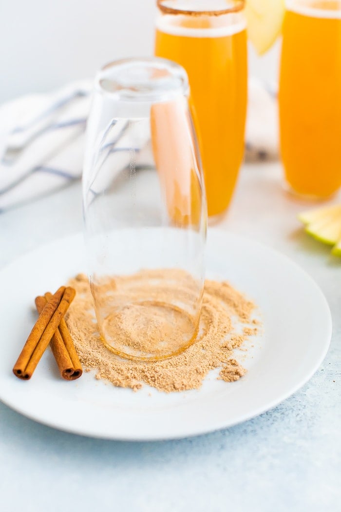 Upside down glass's rim being dipped in cinnamon sugar.