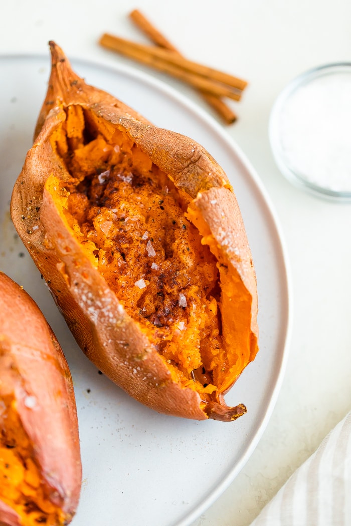 Baked sweet potato on a plate and topped with cinnamon and salt.