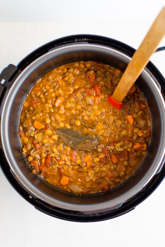 Lentil soup in an instant pot. A wood spoon is in the pot.