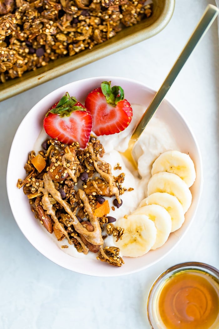 Yogurt bowl topped with granola, a drizzle of peanut butter, banana and strawberry.