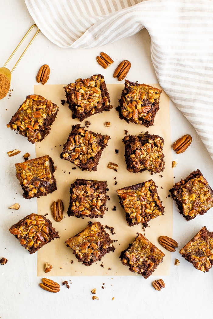 Pecan pie brownies on a table surrounded by pecans.