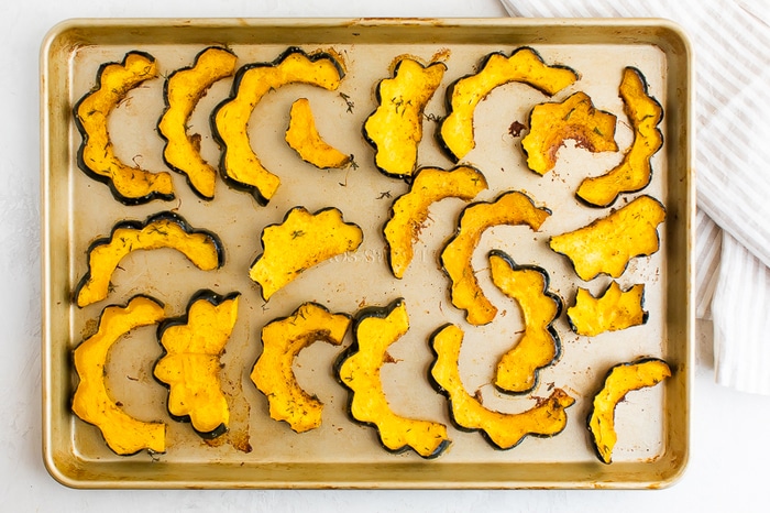 Roasted acorn squash half circles on a cookie sheet.