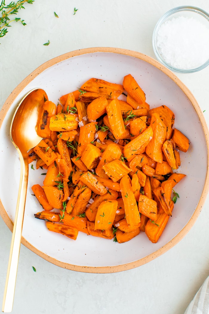 Bowl with herb roasted carrots. A spoon is in the bowl.