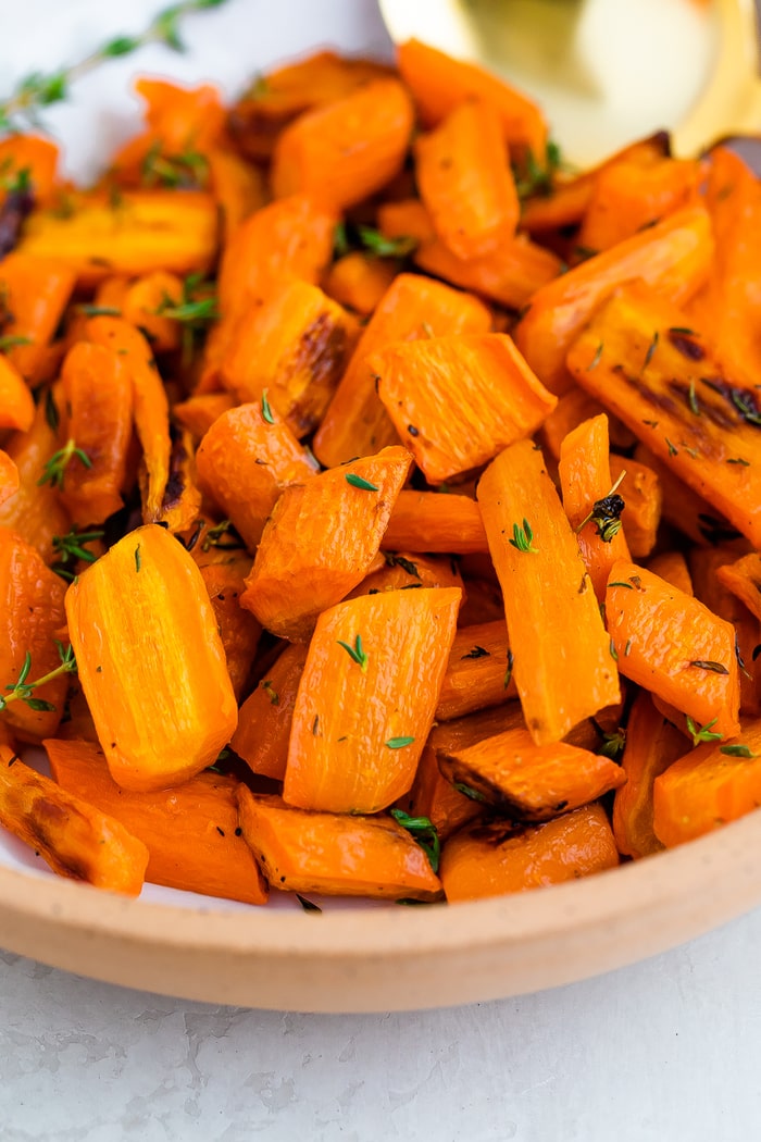 A close up photo of a bowl of carrots with herbs.