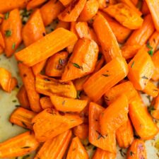 Roasted carrots with herbs on a cooking sheet.