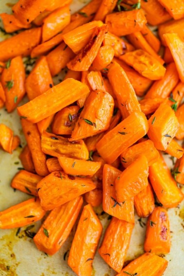 Roasted carrots with herbs on a cooking sheet.
