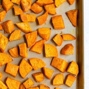 Roasted sweet potato chunks on a sheet pan.