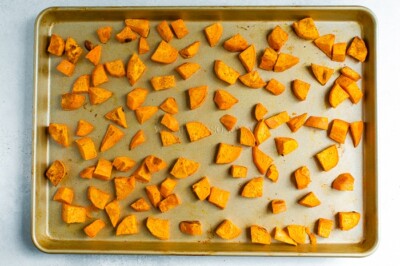A sheet pan with chunks of sweet potato after being roasted.