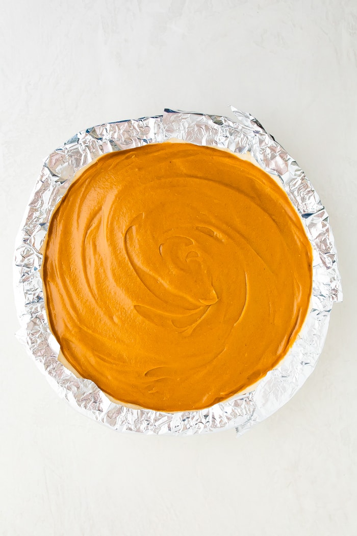 Pie with sweet potato filling before being baked. Foil is crimped over the crust.