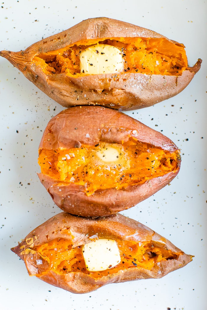 Three baked sweet potatoes topped with butter, salt and pepper.