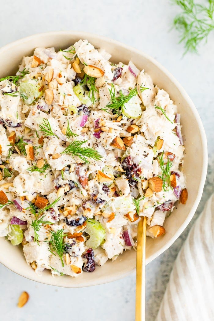 Bowl full of turkey salad topped with fresh dill and chopped almonds.