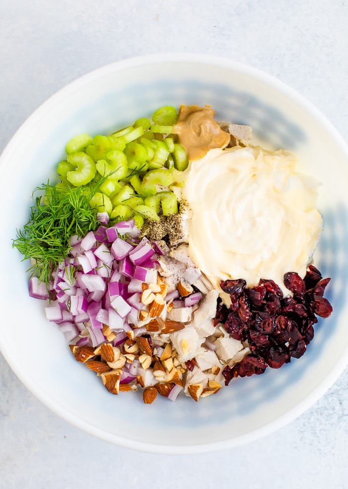 Mixing bowl with mayo, chopped turkey, celery, cranberries, onions and herbs.