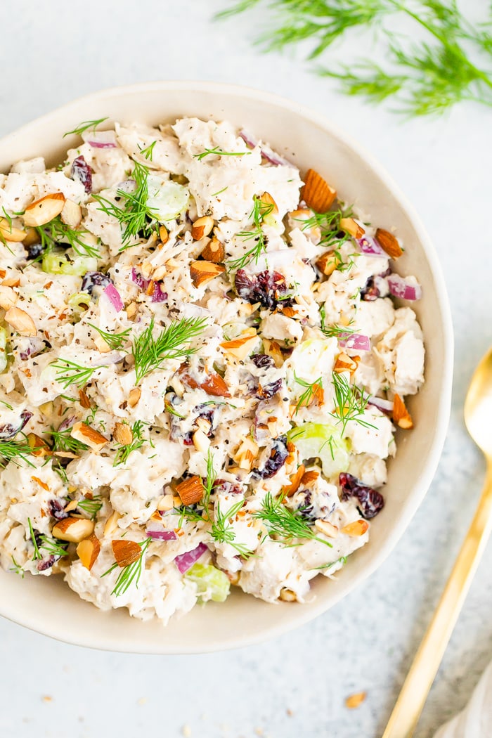 Bowl full of turkey salad topped with fresh dill and chopped almonds.