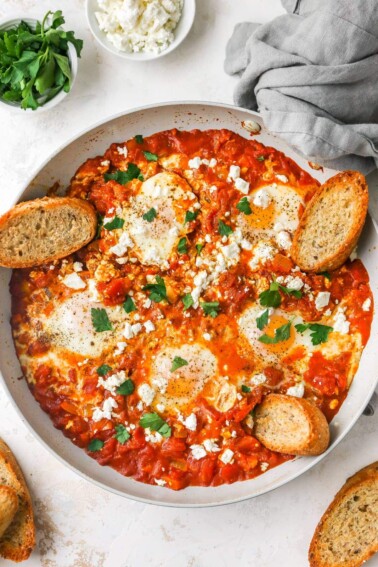 Shakshuka in a large dish served with crusty bread.