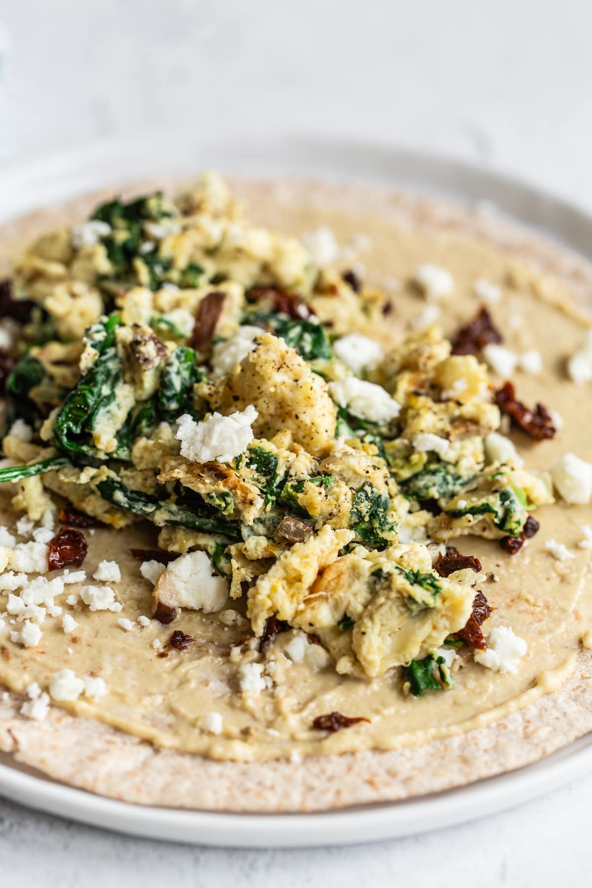 Wrap topped with hummus, eggs, cheese, spinach and sun-dried tomatoes.