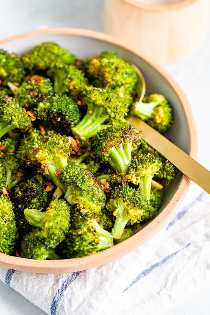 Bowl with roasted broccoli topped with red pepper flakes.