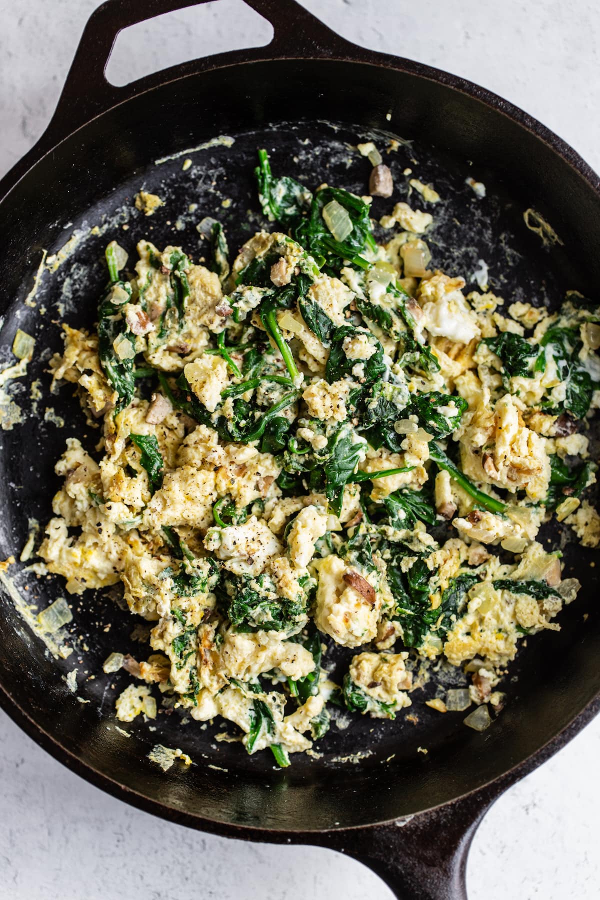 Scrambled eggs with spinach in a cast iron skillet.