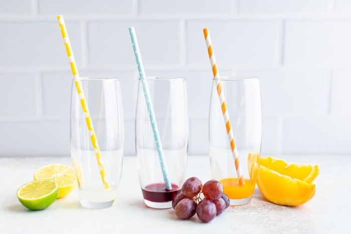 Three glasses with paper straws and a little bit of electrolyte powder mixed with water.