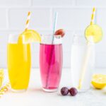 Three glasses of homemade different flavor soda with paper straws.